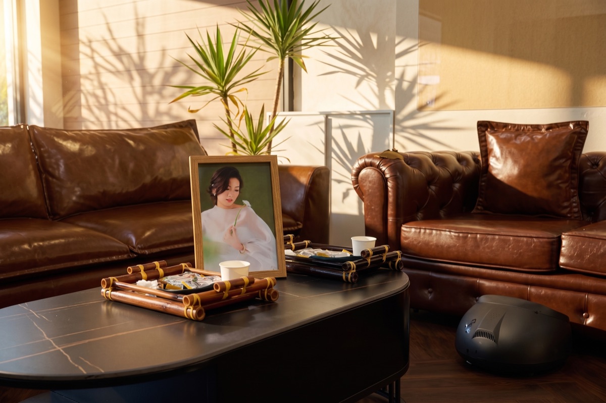 Bàn tiếp khách với sofa da, khung ảnh và ánh nắng trong cơ sở Gạo Nâu Lê Văn Sỹ