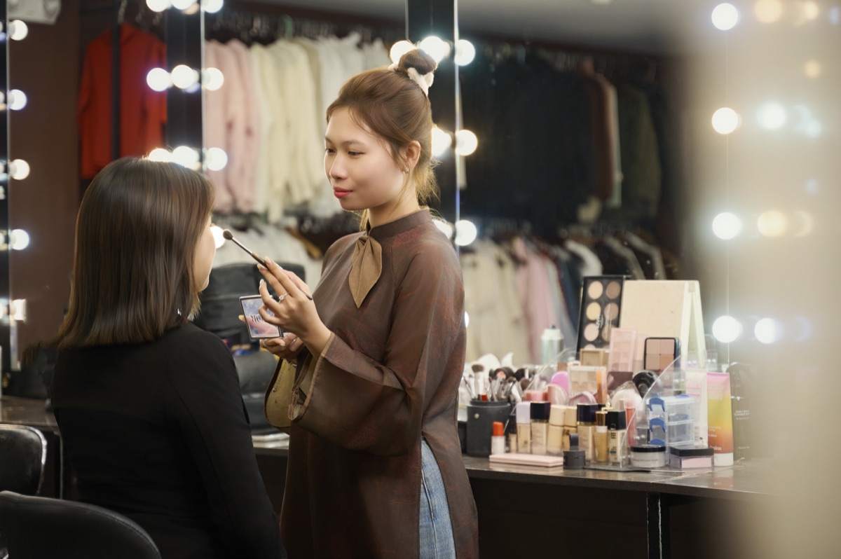 Nhân viên makeup đang trang điểm cho khách tại bàn gương của Gạo Nâu